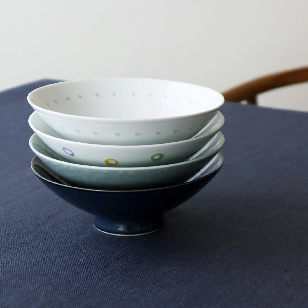 堆疊的四個平茶碗，頂部白色茶碗飾有淺綠色圓點，第二個淺藍色茶碗飾有紫色、黃色和綠色圓環，第三個淺綠色茶碗飾有綠色圓點，最底部為深藍色茶碗。