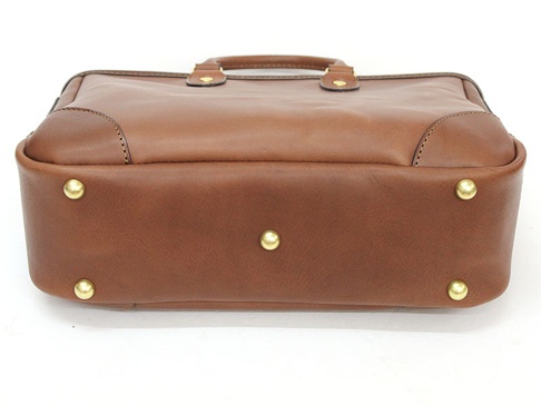 棕色皮革托特包，設有頂部提把、金色金屬釘飾和縫線細節。