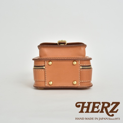 職人手作皮革迷你後背包，採用溫潤的淺棕色皮革，配備黃銅色拉鍊與鉚釘，結構紮實，展現經典工藝。