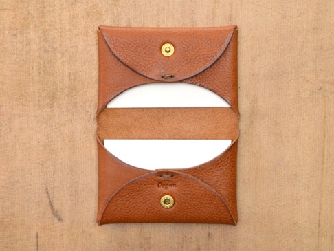 職人手作皮革Organ雙開卡片收納夾，採用棕色荔枝紋皮革製作，雙邊開啟設計，內含白色卡片，以金色釦件固定。