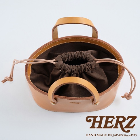 淺棕色皮革束口手提包，配有同色系皮革提把與抽繩，內部為深棕色絨布襯裡，整體呈現簡約設計。