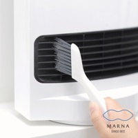 一支白色手柄的灰色細毛縫隙清潔刷，正在清潔白色家電上的黑色格柵。