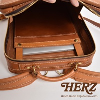 職人手作皮革商務電腦後背包 R-25，展示內部隔層，可容納筆記型電腦，採用 tan 色皮革，搭配白色縫線與黃銅五金配件。