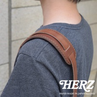 職人手作皮革肩墊，淺棕色皮革，附有縫線細節，實際佩戴在灰色T恤的肩膀上。