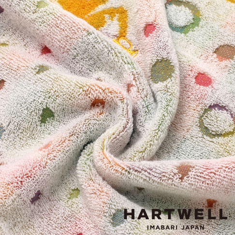 這條Hartwell今治毛巾質地柔軟蓬鬆，表面以柔和的淡色系為基底，交錯佈滿了色彩繽紛的圓點、小象與雨傘等可愛刺繡圖案，呈現出溫馨的童趣風格，右下角印有黑色的Hartwell Imabari Japan品牌字樣。