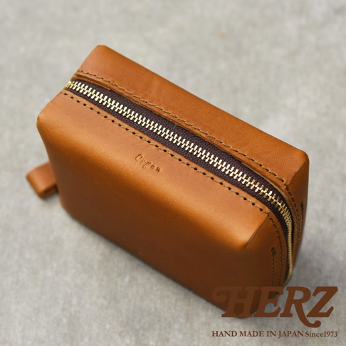 一個棕色皮革箱型收納包，上面印有 Organ 字樣，並配有金色拉鍊。