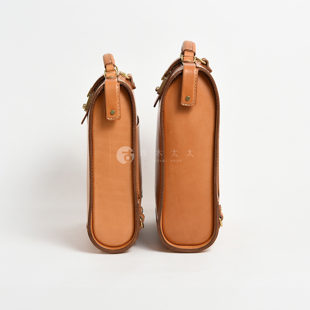 兩個棕色皮革製的杜勒斯商務後背包，一個較小，一個較大，皆有頂部提把、金屬扣件和細節縫線。