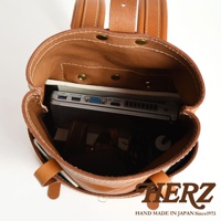 職人手作的駝色皮革後背包，內部展示，可容納筆記型電腦，雙口袋設計，簡約實用。