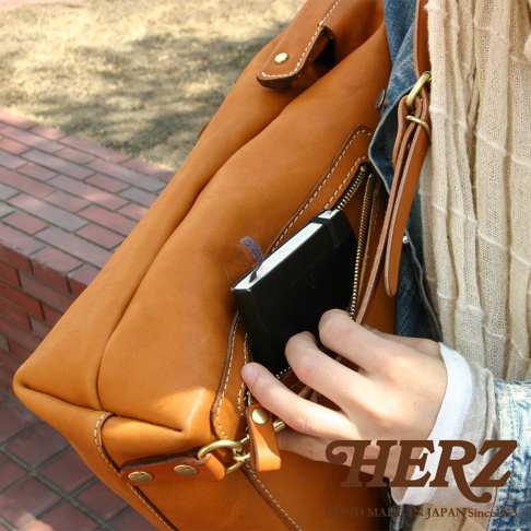 職人手作皮革後背包 R-143，採用厚實的棕色皮革製成，設有拉鍊外袋，可放入小筆記本。包包結構紮實，縫線清晰，帶有復古風格。