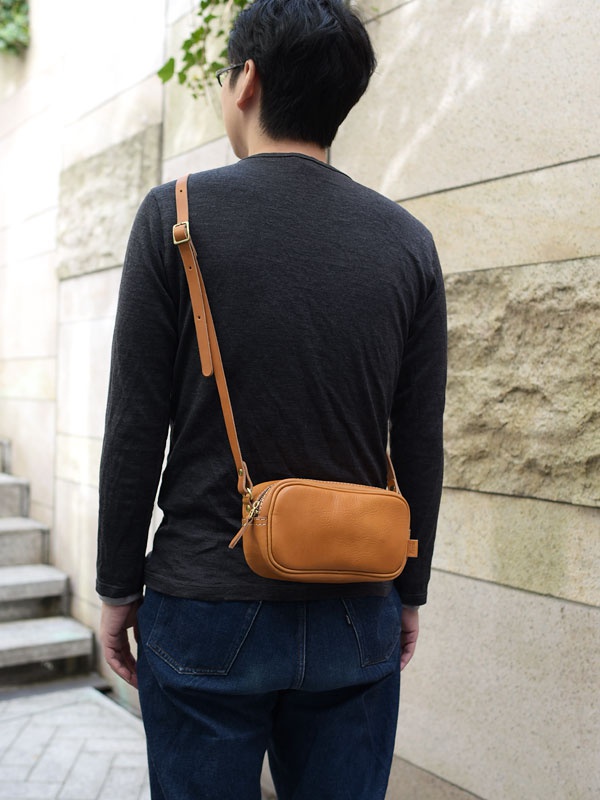 職人手作皮革隨身單肩小包，採用天然棕色皮革製成，質樸紋理，配有可調式皮革背帶和金色拉鍊。
