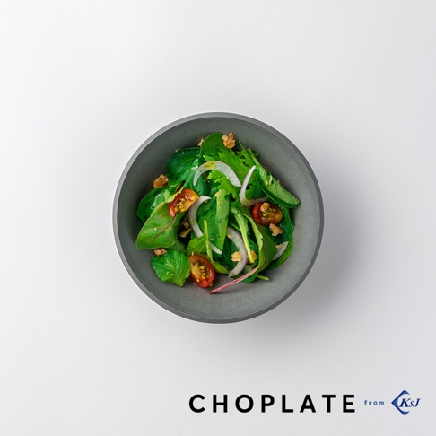 CHOPLATE BOWL 沙拉碗。一個圓形、深灰色的碗，裝有新鮮沙拉，包含綠葉蔬菜、小番茄、洋蔥圈和核桃。