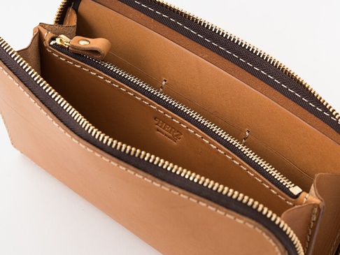 職人手作的淺棕色皮革長夾，拉鍊設計，內部有拉鍊夾層和多個卡槽，整體以雙線縫製，質感細膩。