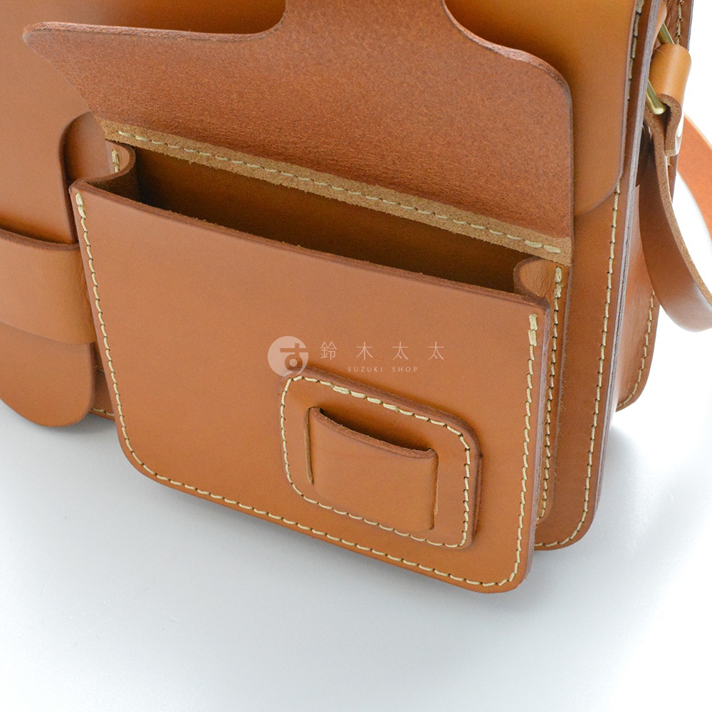 職人手作的單肩包，採用厚實的棕色皮革製成，帶有縫線裝飾和翻蓋口袋設計。