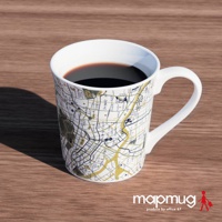 一個裝有咖啡的白色馬克杯，杯身上繪有日文漢字的東京都心地圖，地圖以黃色、深藍色和白色呈現，杯子放在木紋桌面上。