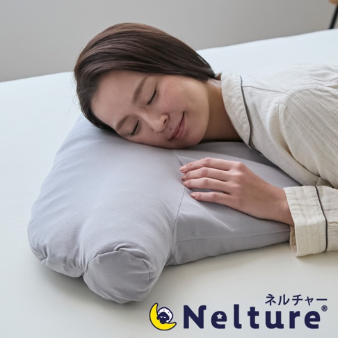 一位女性側睡在一個淺灰色的枕頭上，枕頭設計成有兩個圓形突出物，支撐頸部。