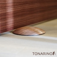 淺木紋地板上放置著一個圓潤的胡桃木色實木門擋，門擋表面有自然的木紋紋理。