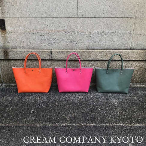 三款京都職人手作肩背手提托特包，分別為亮橘色、桃粉色和墨綠色，皆為皮革材質，設計簡約大方。