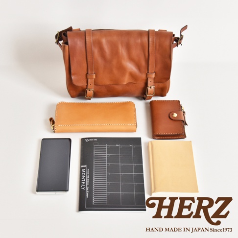 棕色皮革復古郵差包、長夾、短夾、手機、月曆筆記本和筆記本，皆為皮革製。