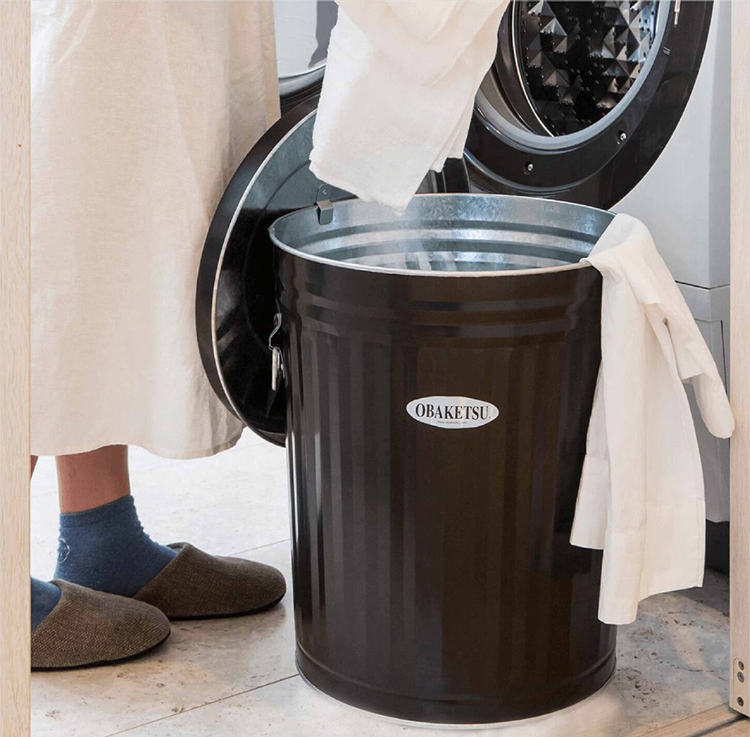 OBAKETSU 標誌著深棕色金屬垃圾桶，用於分類衣物。