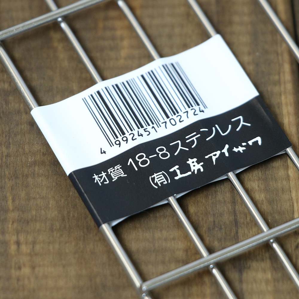 一個方形不鏽鋼瀝油架，由銀色金屬製成，帶有條碼和日文標籤，標示「材質 18-8 不鏽鋼」。