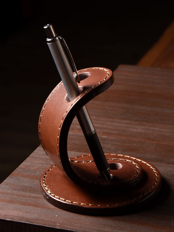 職人手作皮革兩入用筆架，採棕色皮革，以精緻縫線勾勒出螺旋造型，可穩固放置兩支筆。