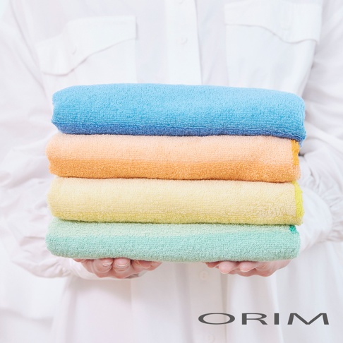 HARUKA 今治耐用絢彩拼接毛巾，堆疊展示四種顏色：藍色、橘色、黃色和綠色，毛巾質地柔軟，觸感舒適。