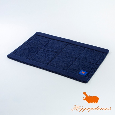 深藍色竹棉混紡厚感浴墊，表面有格紋縫線，右下角有橘色河馬標誌和品牌字樣。