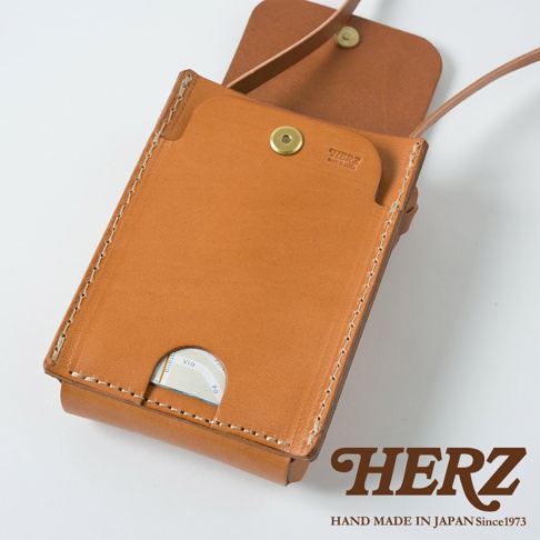 職人手作皮革手機包，大地色系，以手工縫線製成，設有翻蓋及卡槽，可見品牌標誌。