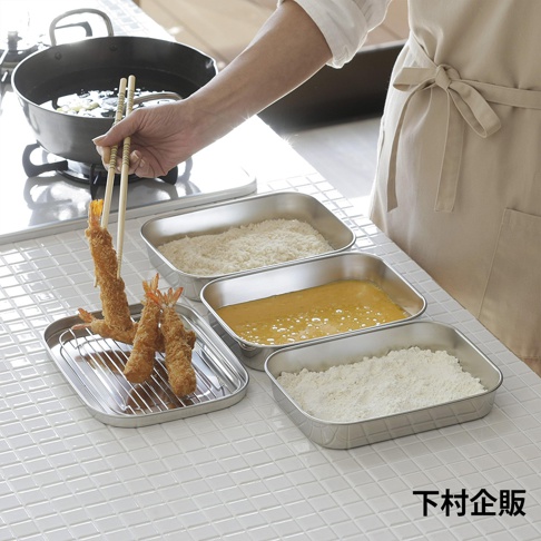 不鏽鋼製備盒組，包含裝有麵包粉、蛋液和麵粉的三個方盤，以及一個裝有炸蝦的瀝水架，由上方手持筷子。