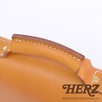 職人手作皮革經典兩用雙扣迷你單肩包，採用天然皮革製成，呈現溫潤的駝色調。包包的提把設計厚實，邊緣以白色縫線精緻縫合，展現細膩的工藝。金屬铆釘固定，增添復古質感。