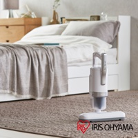 銀色雙氣旋除蹣吸塵器，配有可拆卸的集塵筒和顯示面板，置於臥室地毯上。