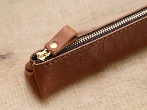 職人手作皮革Organ三角收納筆袋 (GS-28) S，採用棕色牛皮材質，配有金色拉鍊與皮革拉環，縫線精緻，質感厚實，整體呈現簡約復古風格。
