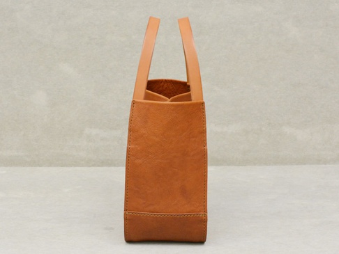 職人手作皮革Organ方形托特包 (G-68) M，呈現簡潔的方形輪廓，採用天然棕色皮革製作，質感細緻。包身縫線清晰，提把為圓弧形設計，整體風格樸實而耐用。