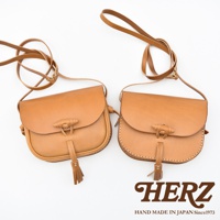 兩款棕褐色皮革流蘇側背包，均採用圓潤飽滿的設計，附有可調整長度的長背帶和獨特的木質紋理開合扣，以及皮革流蘇裝飾。