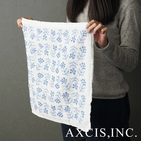 一條白色純棉花草紗布大拭巾，印有藍色花草圖案，由一人手持展示。
