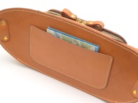 淺棕色皮革斜背包，設有金色拉鍊和皮革拉環，包身前方有一個開放式插袋，內有幾張卡片或地圖。