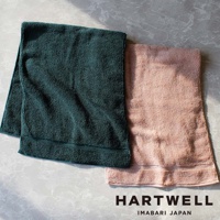 兩條今治毛巾，一條為深綠色，另一條為淺粉色，皆為純棉材質，觸感柔軟，帶有精緻的壓紋邊緣。