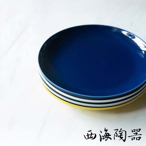 波佐見燒 Common 陶瓷料理盤，疊放展示，上方為深藍色，下方依序為白色、灰色與黃色盤，皆為圓形設計。