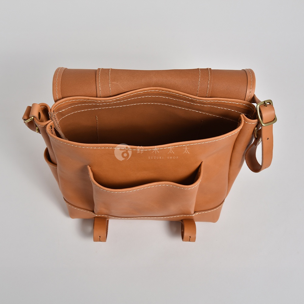 職人手作皮革復古郵差包，淺棕色，頂部視角，展示包包內部及外部口袋，皮革材質，縫線明顯，配有黃銅色金屬扣環。