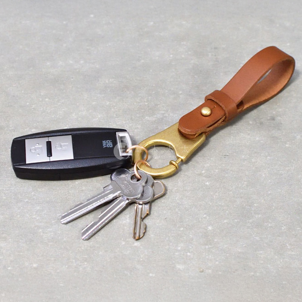 職人手作皮革鑰匙圈，附有黃銅色D型環及金屬釦，搭配汽車遙控器與鑰匙組。