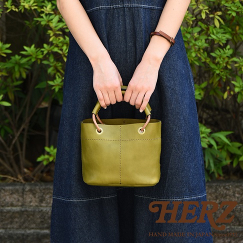 橄欖綠皮革提把大開口午餐袋，採用加厚皮革材質，設計簡潔，提把處有銅環裝飾，適合日常攜帶。