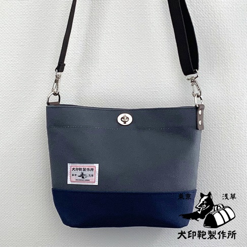 犬印純綿帆布雙色迷你側背包，深灰色包身搭配海軍藍底部，設有轉鎖開合及品牌標籤。