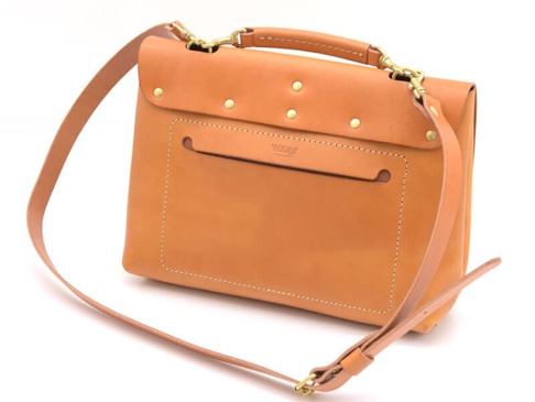 職人手作的棕色皮革雙扣三用後背包，包身線條簡潔，前方有方形口袋設計，搭配金屬扣環與可調節的皮革背帶，展現經典質感。