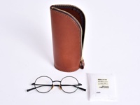 職人手作皮革直立式收納筆袋，經典棕色，附有拉鍊開合。下方擺放一副黑色圓框眼鏡及一包眼鏡清潔濕巾。