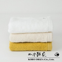 白色、米色、芥末黃三條超細纖維毛巾堆疊，毛巾質地蓬鬆柔軟，呈現高密度織法。