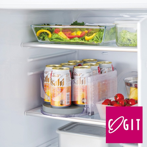 冰箱層架上，一個透明的圓形旋轉收納盤，上面擺放著一排鋁罐飲料，飲料罐為白色和金色，標籤上有日文文字。收納盤旁有一個透明的塑膠飲料架，架內有更多相同飲料。右側有一個透明的玻璃容器，裝有小番茄，容器後方有切塊的黃色和紅色甜椒，以及綠色蔬菜。