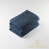 深藍色純棉浴巾兩條堆疊，頂部浴巾一角縫有棕色品牌標籤，材質蓬鬆柔軟。