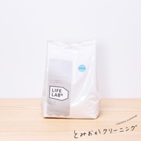 白色補充包洗衣粉，正面有淺灰色標籤，標籤上有「LIFE LAB°」字樣和日文說明。右側有一個圓形藍色貼紙，上面寫著「ORIGINAL」。產品置於木質檯面上，背景為白色。