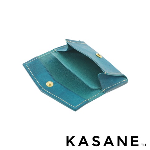 北海道KASANE品牌職人手作義大利Margot皮革迷你雙折短夾，藍綠色皮革，帶有金色按扣，內部分層設計，露出內部皮革紋理，展示於白色背景上。