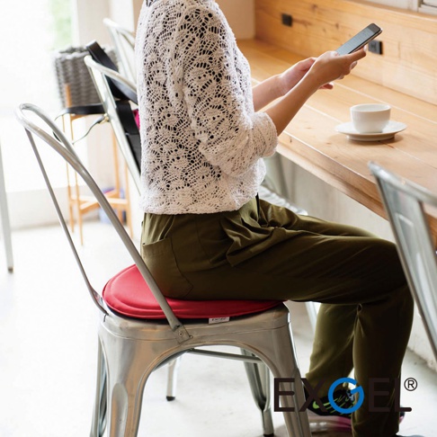 MARU PUNI 圓座墊，紅色，圓形，織物材質，置於金屬椅上，一位女士坐著使用手機。